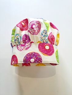 a white hat with donuts on it is hanging from the wall next to a pair of scissors