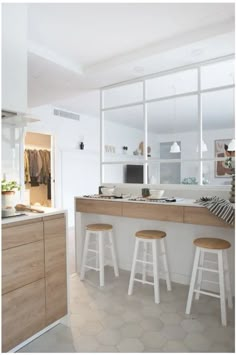 a kitchen with three stools in front of the counter and an open window to the outside