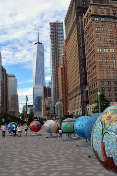 people are walking around in the middle of a city with tall buildings and colorful balls