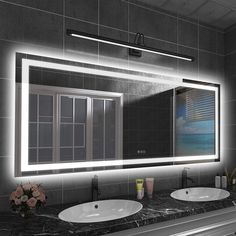 a bathroom vanity with two sinks and a large mirror above it that lights up the room