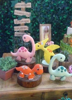 there are many small toy dinosaurs on the table with plants and pictures in front of them