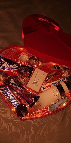 a heart shaped box filled with assorted chocolates and candies on a bed