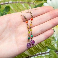 Tiny gemstones link to a amethyst pebbles to create these elegant rainbow drop earrings. Wear these with your favorite gemstone necklaces for a unique boho look or let them shine on its own, either way, you will love the way they look and feel the moment you put them on. GEMSTONE MEANINGRed - carnelian for confidenceYellow - citrine for willpowerLight green - peridot for abundanceDark green - malachite for transformationPurple - amethyst for spirituality DIMENSIONSDrop length: approximately 2.75 Cotton Jewelry, Gemstone Necklaces, Green Malachite, Jewelry Card, Green Peridot, Shine On, Boho Look, Jewelry Pouch, Gemstone Necklace