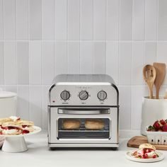 a silver toaster oven sitting on top of a counter next to plates and utensils