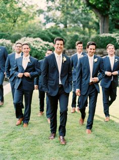 a group of men in suits walking across a lush green field