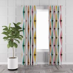 a potted plant sitting next to a window with colorful curtains on the windowsill