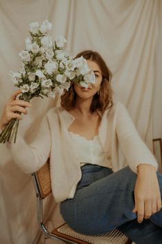 a woman sitting in a chair holding flowers