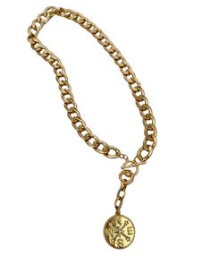 This snake chain necklace commands attention with its bold design and luxurious appeal. Crafted from gleaming gold, each link in the chain is substantial, exuding a sense of opulence and strength. At its center lies the focal point of the piece: a large gold charm shaped like a compass rose, with distinct north, south, east, and west directions. The charm is intricately detailed, its smooth surface catching the light and casting a warm, radiant glow. Completing the necklace is a gold toggle clasp, adding both functionality and style to the piece. The total length is 20 inches with the clasp right at 18 inches. When worn, this statement necklace becomes more than just an accessory; it becomes a symbol of confidence, sophistication, and timeless elegance. Its weight on the neckline serves as Gold-plated Round Pendant Charm Necklaces, Gold-plated Charm Necklaces With Round Pendant, Gold-plated Necklace With Round Pendant, Gold Plated Charm Necklaces With Round Pendant, Gold Plated Charm Necklace With Round Pendant, Tarnish Resistant Brass Pendant Chain Necklace, Luxury Tarnish-resistant Oval Link Chain Necklace, Gold-tone Chain Charm Necklace With Round Pendant, Brass Pendant Necklace With Gold Chain