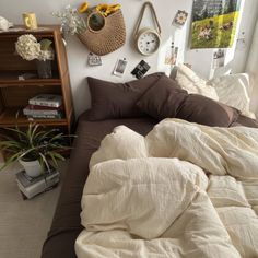 an unmade bed with many pillows and pictures on the wall