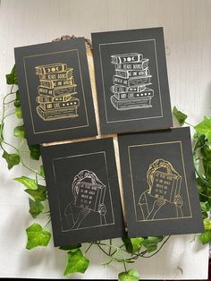 four black and gold books are sitting on a table next to some green planters