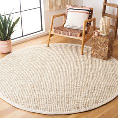 a living room area with a chair, rug and potted plant on the floor