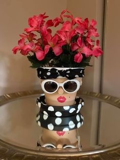 a vase with flowers and sunglasses on top of a glass table in front of a mirror