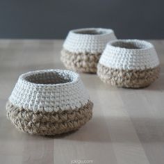 two crocheted baskets sitting on top of a wooden table