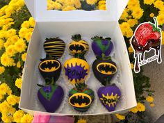 chocolate covered strawberries decorated to look like batman and strawberrys with yellow flowers in the background