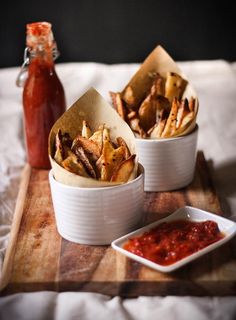 two white bowls filled with food sitting on top of a wooden tray next to a bottle of ketchup