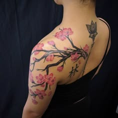 the back of a woman's shoulder with pink flowers on it and a bird