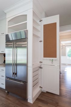 a stainless steel refrigerator in a kitchen with white cabinets and wood flooring on the side