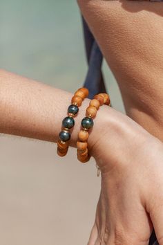 "A Hawaiian treasure, this beaded bracelet features chunky wooden beads carved from sandalwood, delicate gold-filled accents and a single black Tahitian pearl for good measure. ✦ DETAILS ✦ ✧ Name: Roselani (rose-LAH-nee) ✧ Adjustable Length from: 7\"-8.5\" ✧ Genuine Tahitian Pearl 8-10mm AA-AAA quality; tone and shape varies. ✧ 8mm Fragrant Sandalwood Beads ✧ 14kt Gold Filled Components, Extender, and Clasp. ✧ All Ke Aloha Jewelry pieces come packaged thoughtfully, beautifully, and ready for gif Traditional Wooden Beads Bracelets For Beach, Black Pearl Bracelet, Tahitian Pearl Bracelet, Hawaii Jewelry, Wood Bead Bracelet, Tahitian Black Pearls, Heirlooms Jewelry, Beaded Bracelets Diy, Bracelet Beaded