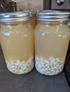 two jars filled with white beans sitting on top of a counter