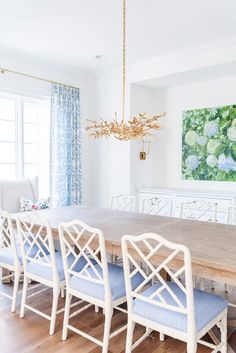 a dining room table with blue chairs and a chandelier hanging from the ceiling