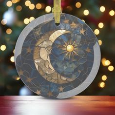 a stained glass ornament hanging on a table with a christmas tree in the background