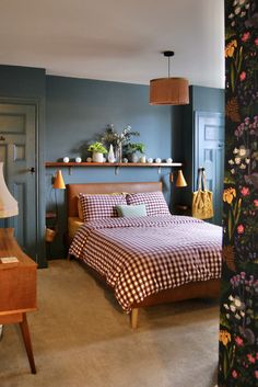 a bed room with a neatly made bed next to a wall mounted shelf filled with vases