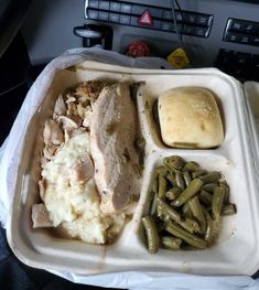 a plastic container filled with meat, mashed potatoes and green beans