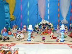 there are many figurines on the table with blue curtains behind them and other decorations