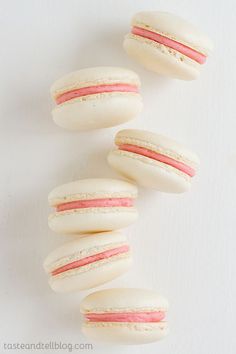 four macaroons with pink and white frosting on them are arranged in a row