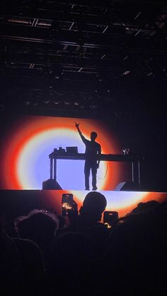 a man standing on top of a stage with his arms in the air as he speaks to an audience