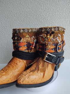 Meet 'Orange is the New Black'! She's spicy.  Trouble always seems to find her. But she's a good girl at heart.   Elevate your style with these upcycled blingy cowboy boots - a blend of eco-chic and feminine charm. This pair, uniquely crafted from a blend of new and repurposed materials, is adorned with  a mix of neck ties, rhinestones, feathers,  belts, pins, trims, and lace.   These pre-loved boots not only make a fashion statement but also a sustainable choice for the conscious fashionista.  Part of the process of crafting these is taking a full height boot then cutting and folding to make this fabulous bootie!  Festivals and Carnivals, here we come! As a bonus, we'll ship in a plastic shoe bin which can also be used to store these beauties. Brand: Diego's Marked Size: US Mens 6 (approx Bohemian Moto Boots For Festival In Fall, Bohemian Snip Toe Boots For Festival, Bohemian Snip Toe Festival Boots, Bohemian Brown Boots For Rodeo, Bohemian Brown Boots For Western-themed Events, Handmade Western Boots For Fall, Handmade Brown Western Boots, Shoe Bin, Plastic Shoes