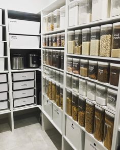 an organized pantry with white bins and clear containers on the shelves, labeled from housetohome