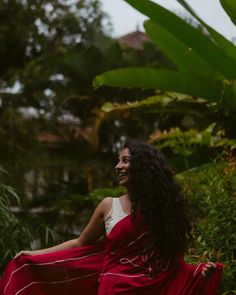 a woman in a red and white dress sitting on the ground with her arms around her body