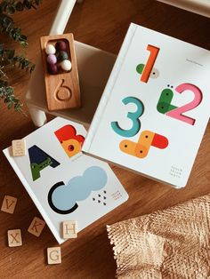 two children's wooden blocks with numbers and shapes on them next to a plant