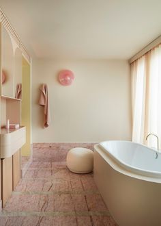 a bath room with a large tub and a sink next to a window on the wall