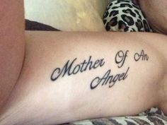 a woman laying on top of a bed with a tattoo on her arm that says mother of an angel