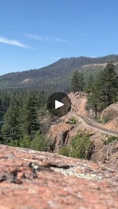 a view from the top of a mountain looking down at a road and trees on it