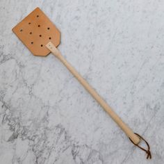 a wooden spatula with holes in it on a marble surface