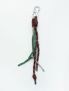 a keychain with two pieces of green and red string attached to it on a white surface