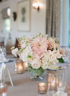 the centerpieces on this table are filled with flowers, candles and napkins