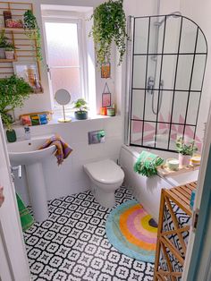 a white bathroom with a rainbow rug and potted plants on the window sill