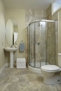 a bathroom with a shower, toilet and sink in it's corner stall area