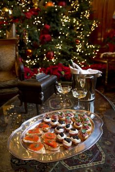 a platter filled with appetizers sitting on top of a table next to a christmas tree