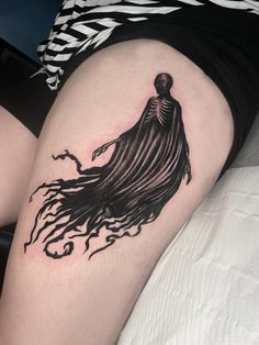 a woman's thigh with a black and white tattoo design on her leg that has a skeleton in the shape of a ghost