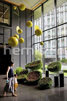 a woman and child are walking in an office lobby with large windows that look out onto the city