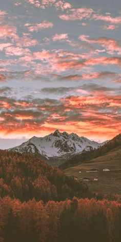 the sky is pink and orange as the sun sets in the distance over mountains with snow on them