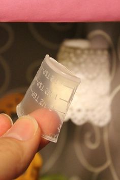 a hand holding a small plastic measuring cup with thermometer on it's side