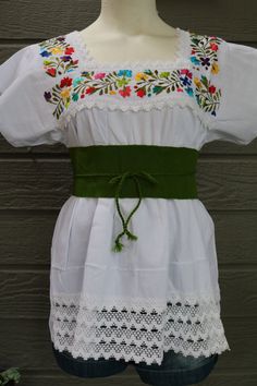 Hand embroidered floral blouse with short sleeves and crochet lace accents on the top section. The cotton fabric is perfect for the Spring/Summer season. *Waist belt sold separately. 100% Cotton Made in Mexico Measurements:  S/M - Bust (armpit to armpit): 36 inches - Waist: 42 inches - Sleeve Length: 8.25 inches - Total Length (shoulder to bottom hem): 26 inches L/XL - Bust (armpit to armpit): 44 inches - Waist: 50 inches - Sleeve Length: 9 inches - Total Length (shoulder to bottom hem): 27.75 i Short Sleeve Cotton Dresses With Lace Work, Cotton Dresses With Lace Work And Short Sleeves, Fitted Short Sleeve Blouse With Embroidered Hem, Fitted Short Sleeve Top With Embroidered Hem, Fitted Short Sleeve Blouse With Multicolor Embroidery, Short Sleeve Embroidered Top For Festival, Fitted Multicolor Embroidered Short Sleeve Blouse, Fitted Multicolor Embroidery Blouse With Short Sleeves, Fitted Short Sleeve Embroidered Top