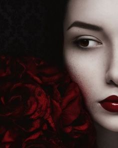 a woman's face with red lipstick and flowers in front of her, on a black background