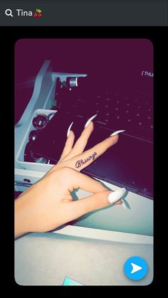 a woman's hand with two fingers on top of a computer keyboard and an arrow tattoo